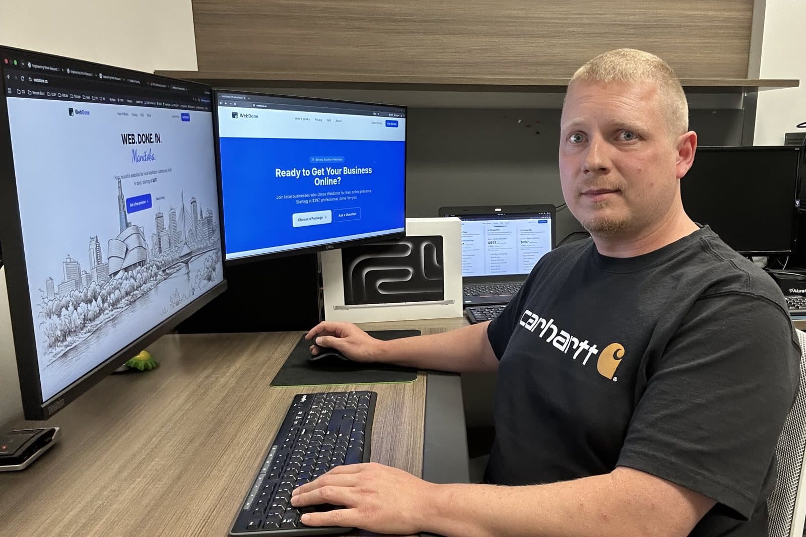 Alex Luft, owner of WebDone, at his desk in Blumenort, Manitoba with the WebDone site on screen